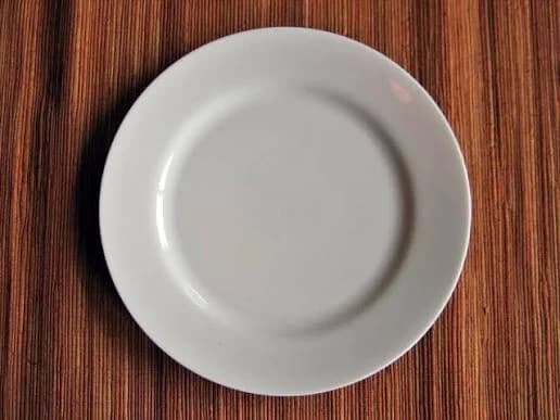 A white plate on a wooden surface.