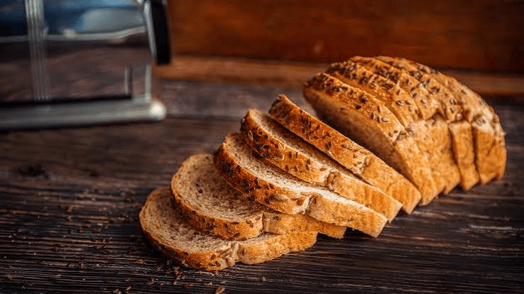 A loaf of bread sliced into several pieces on a wooden table.